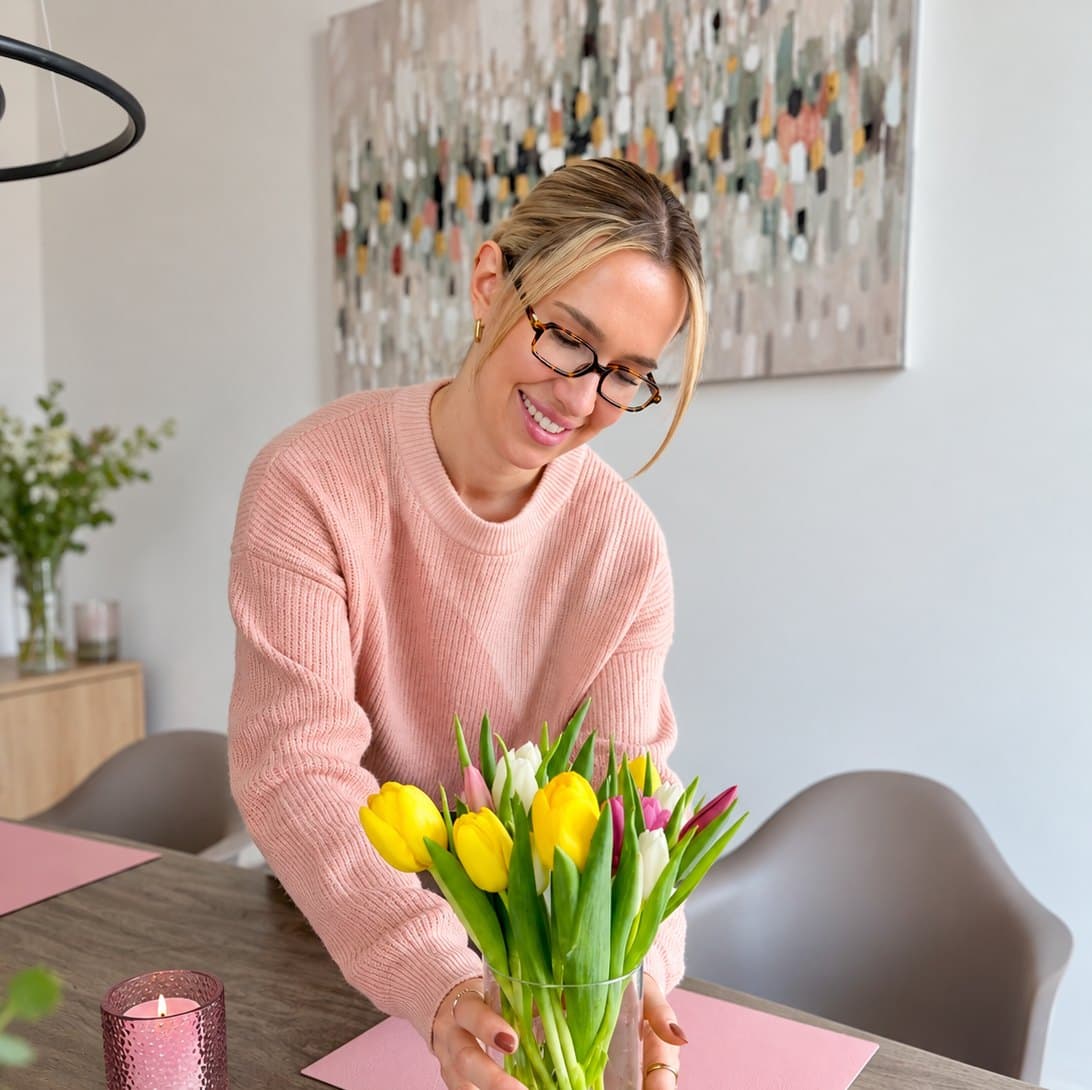 Betreuungskraft stellt frische Tulpen auf den Esstisch
